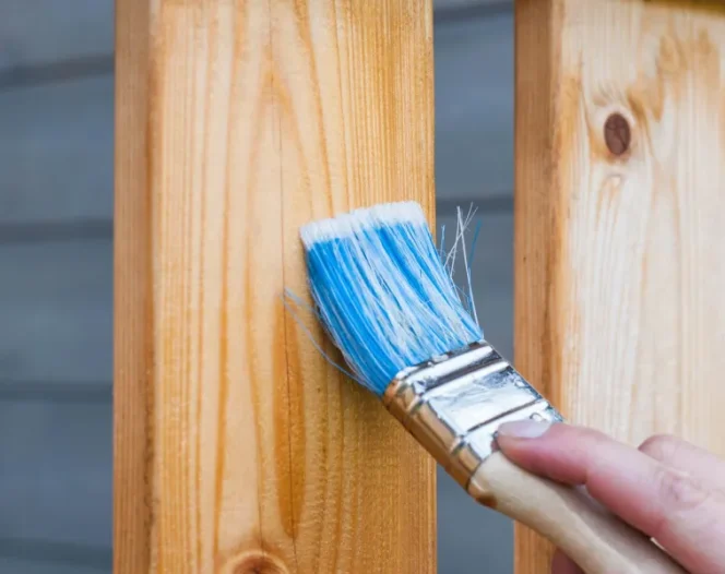 Close up of an application of varnish on a section of a wooden fence